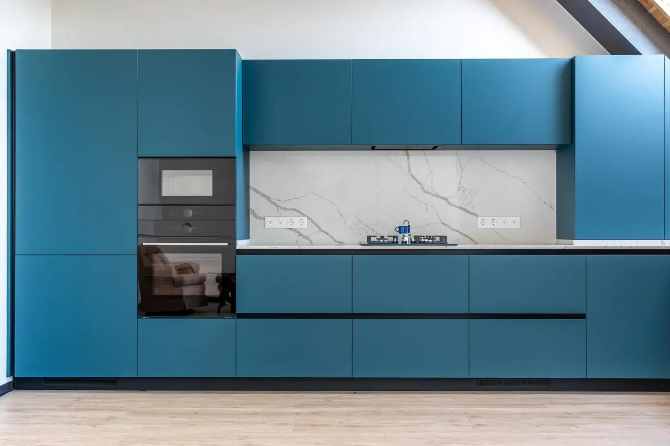 A kitchen featuring a gas stove, a marble wall, and matte blue cabinetry.
